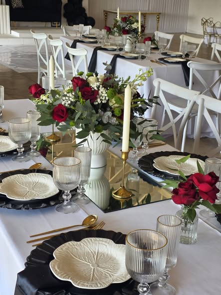 Elegant table setting at Muano, red roses, gold candlesticks, black charger plates and crystal glassware